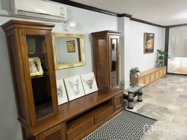 联排别墅 出租在Prawet, Bangkok - 走廊一侧木质展示柜与矮柜，采光良好。