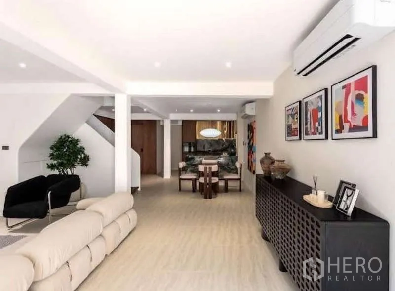 Townhouse for sale in Sathon, Bangkok - Open-plan living and dining space with artwork, air conditioning and sideboard.