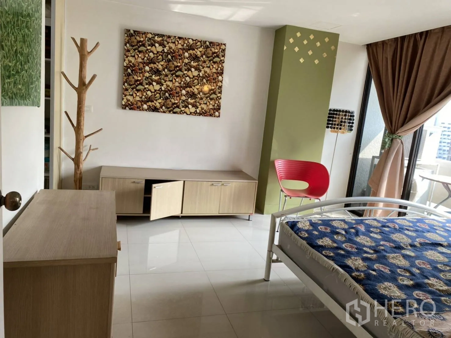 คอนโด ให้เช่าในPathum Wan, Bangkok - ห้องนอนกว้างพื้นกระเบื้อง ตู้เตี้ย งานศิลปะ และประตูเปิดสู่ระเบียง