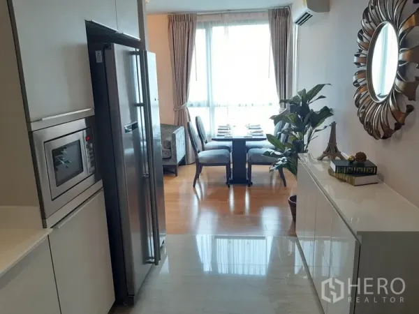Condominium for rent in Watthana, Bangkok - Compact kitchen with stainless fridge, built-in microwave, and a bright dining area by a large window.
