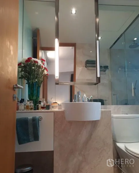 Condominium for rent or sale in Sathon, Bangkok - Modern bathroom with vessel sink, marble vanity, glass shower enclosure and soft lighting.