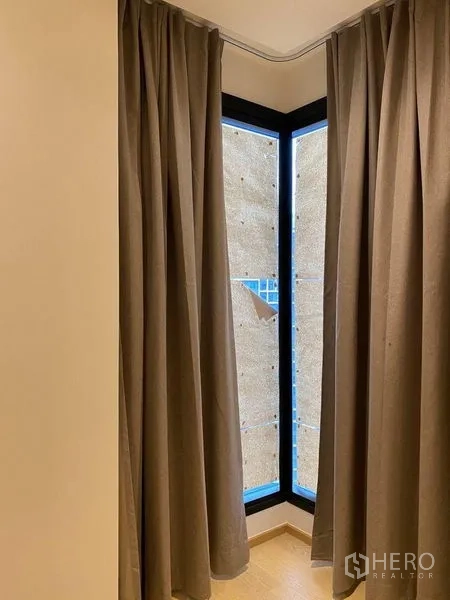 คอนโด ขายในDin Daeng, Bangkok - มุมหน้าต่างกระจกบานสูงกรอบสีดำพร้อมผ้าม่านสีเทาในคอนโดกรุงเทพฯ