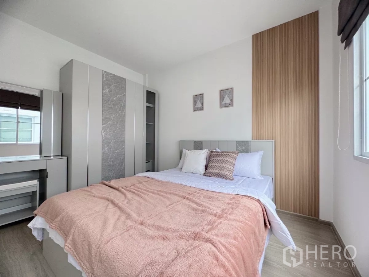 联排别墅 出租在Prawet, Bangkok - 次卧带内置衣柜与床头木饰面。