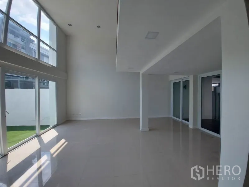 ทาวน์เฮาส์ ขายในWang Thonglang, Bangkok - ห้องนั่งเล่นเพดานสูงโปร่งสว่าง พร้อมกระจกสูงจรดเพดานเปิดสู่สนามหญ้า