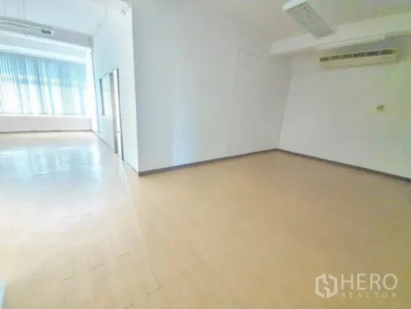 Office Space for rent in Bang Na, Bangkok - Empty office room with window blinds, wood flooring, fluorescent lighting and wall-mounted air conditioning.