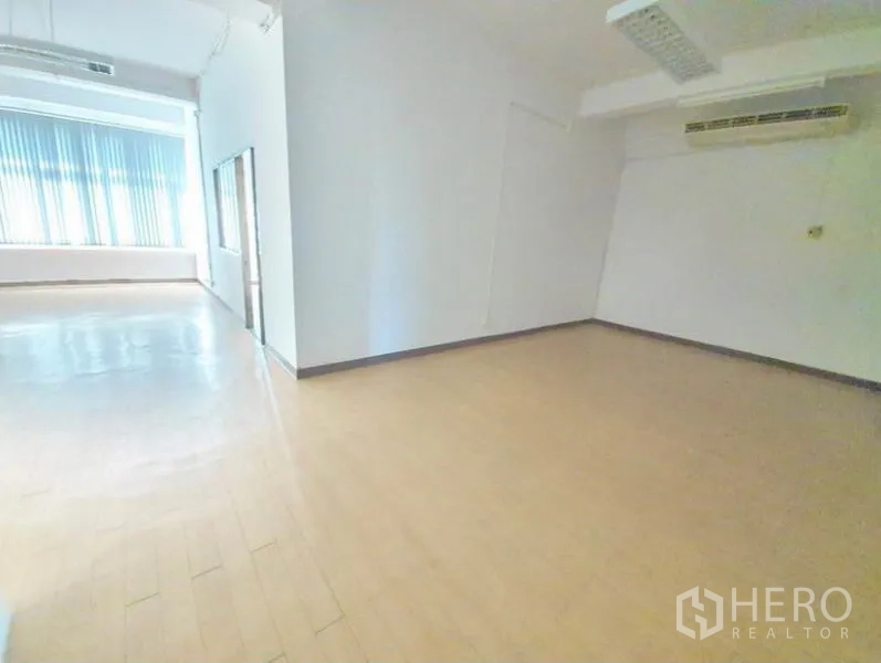 Office Space for rent in Bang Na, Bangkok - Empty office room with window blinds, wood flooring, fluorescent lighting and wall-mounted air conditioning.