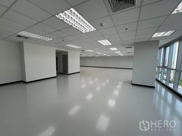 Office Space for rent in Watthana, Bangkok - Corner office floor with window frontage, structural columns, and doorway to service area, filled with natural light.