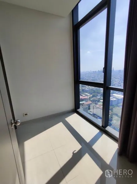 Condominium for rent in Watthana, Bangkok - Bright multipurpose room with full-height window and long city view.