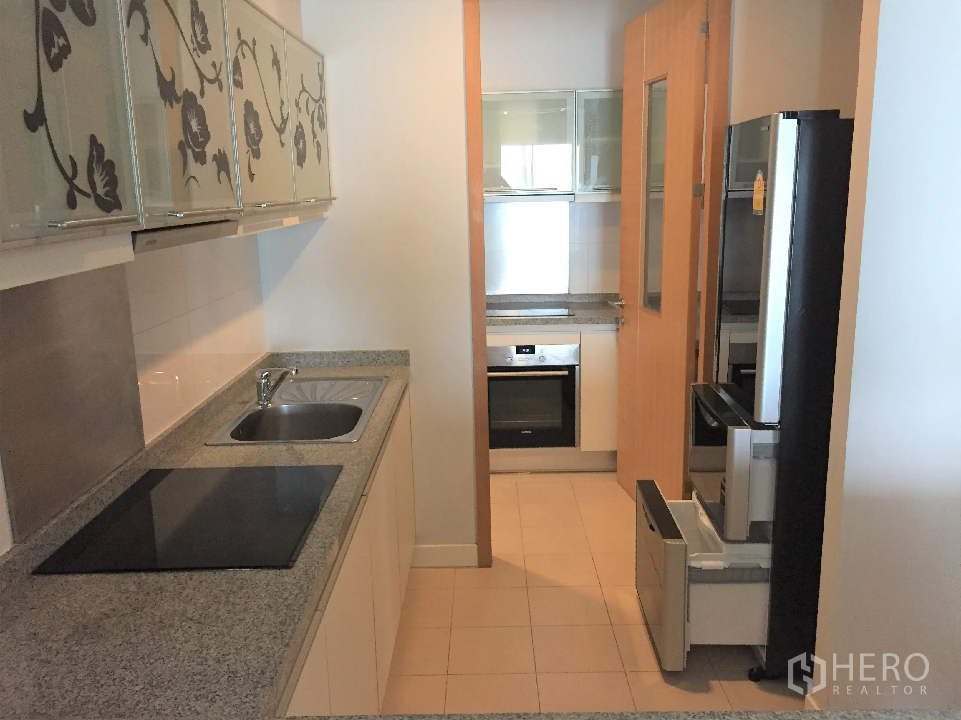 คอนโด ให้เช่าหรือขายในKhlong Toei, Bangkok - ครัวแบบแกลลีย์ เคาน์เตอร์หินแกรนิต เตาไฟฟ้า เตาอบบิวท์อิน และตู้ลายดอกไม้กระจก