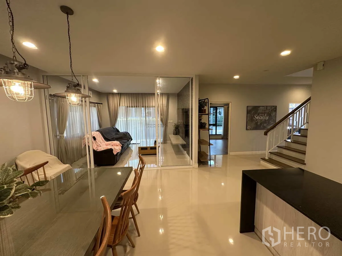 บ้าน ให้เช่าหรือขายในLam Luk Ka, Pathum Thani - มุมมองจากห้องทานอาหารไปยังบันไดและผนังกระจก พร้อมหน้าต่างบานใหญ่.