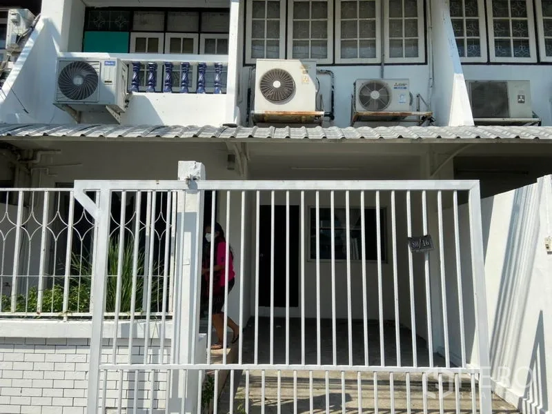 ทาวน์เฮาส์ ให้เช่าในWatthana, Bangkok - ด้านหน้าทาวน์เฮ้าส์มีกำแพงรั้ว ประตูเหล็ก และที่จอดรถในร่มพร้อมแอร์หลายตัว.