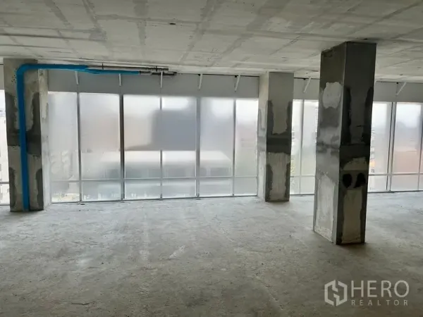 Office Space for rent in Sathon, Bangkok - Corner office area with frosted floor-to-ceiling glass, concrete pillars and visible blue conduit.