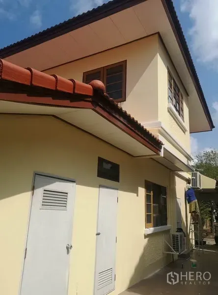 独立式住宅 出售 - 米黄色两层外立面，白色檐口与设备间门。