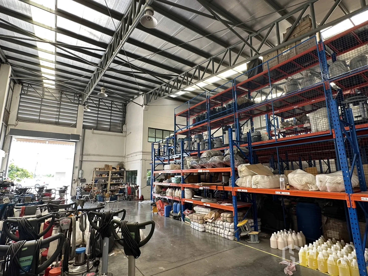 工厂 出租或出售在Pathum Thani - 仓库内部高挑空间，天窗与重型货架一字排开。