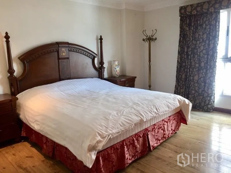 Condominium for rent or sale in Pathum Wan, Bangkok - Primary bedroom with large wooden headboard, bedside tables and natural light from the window.