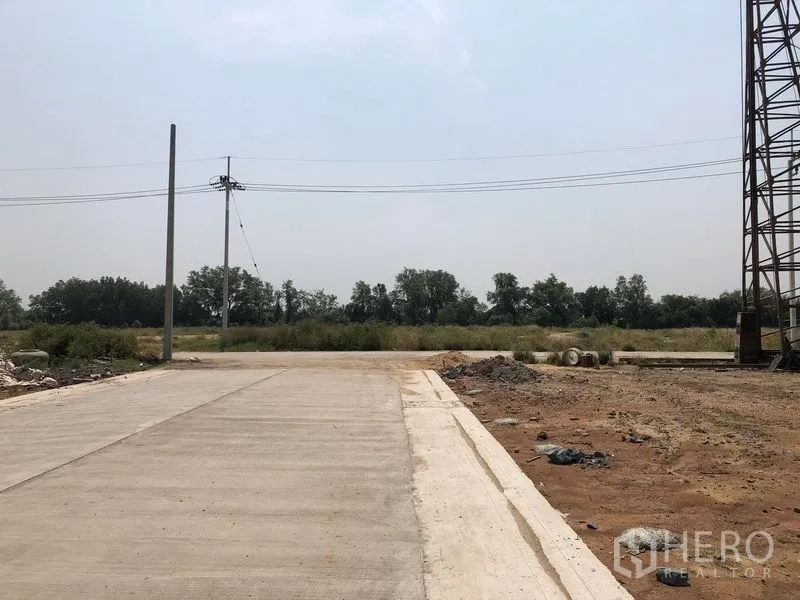 地 出售在Mueang Samut Sakhon, Samut Sakhon - 通往地块的混凝土支路，前方绿地与电力线，地面已清理