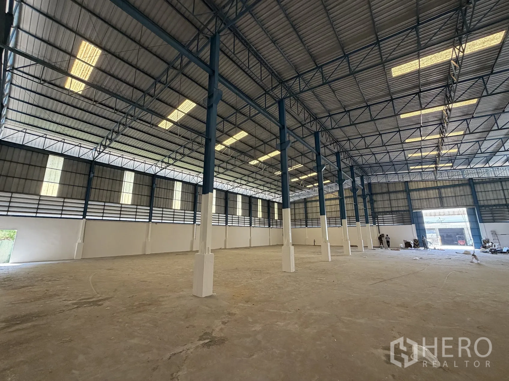 Factory for rent in Bang Sao Thong, Samut Prakan - Spacious warehouse interior with high ceiling, steel trusses, tall columns and bright roof panels.