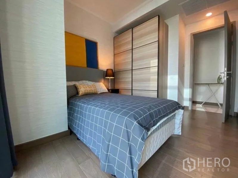 Condominium for rent in Watthana, Bangkok - Second bedroom with wardrobe, window drapes and check-pattern bedding.