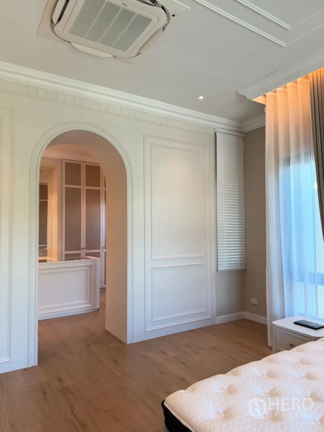Detached House for rent in Saphan Sung, Bangkok - Primary bedroom showing arched doorway to walk-in closet and tall windows with curtains.