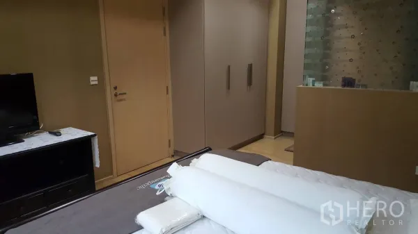 คอนโด ให้เช่าในKhlong Toei, Bangkok - ห้องนอนคอนโดในกรุงเทพฯ มีตู้เสื้อผ้าบิวท์อิน โต๊ะวางทีวี และฉากกระจกฝ้า