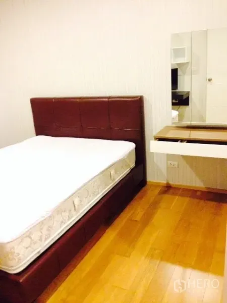 公寓 出租在Phaya Thai, Bangkok - 温馨卧室，软包床、木地板，并设有壁挂式梳妆台与镜柜。