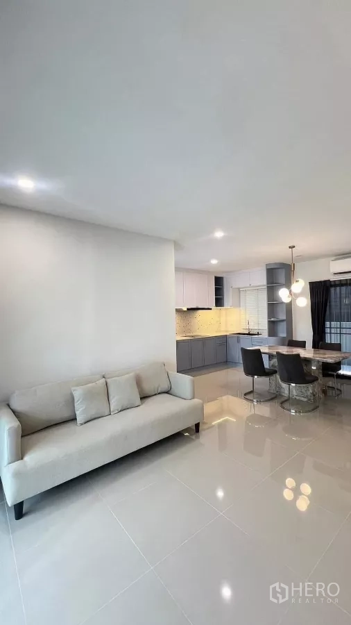 Townhouse for rent in Bang Phli, Samut Prakan - Bright living–dining area with sofa, tiled floor and full fitted kitchen.