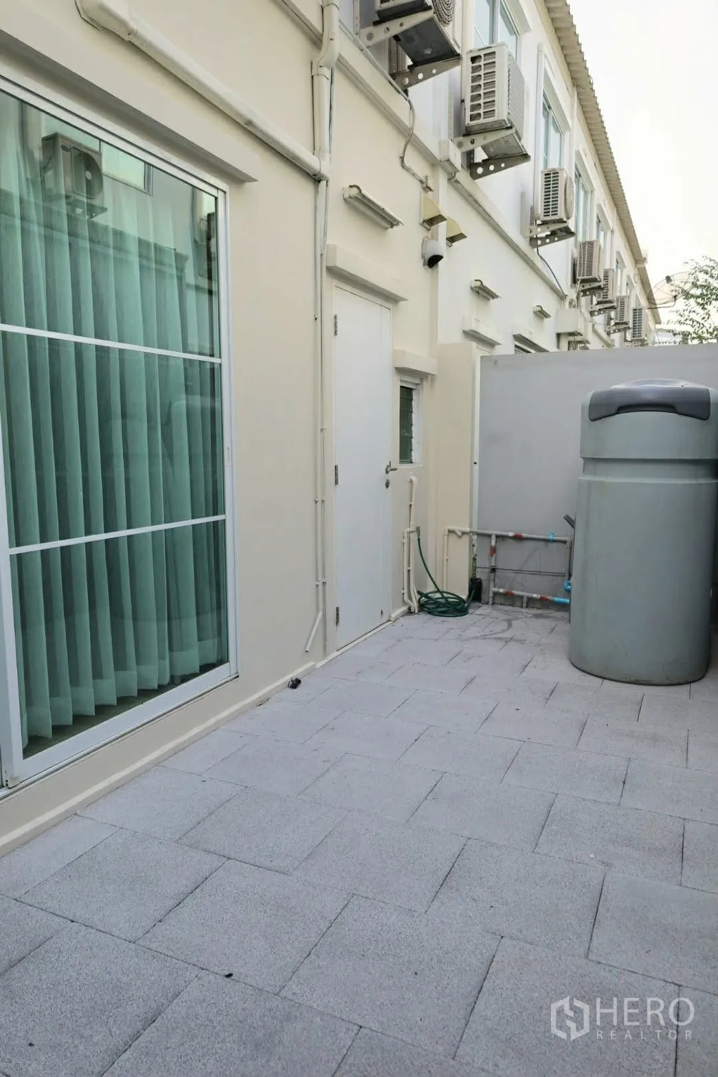 联排别墅 for rent in Prawet, Bangkok - 后院露台，带推拉玻璃门、蓄水桶、软管及外挂机。