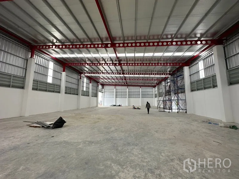 Warehouse for rent or sale in Lam Luk Ka, Pathum Thani - Open warehouse floor with skylights, red beams and ventilated side windows.