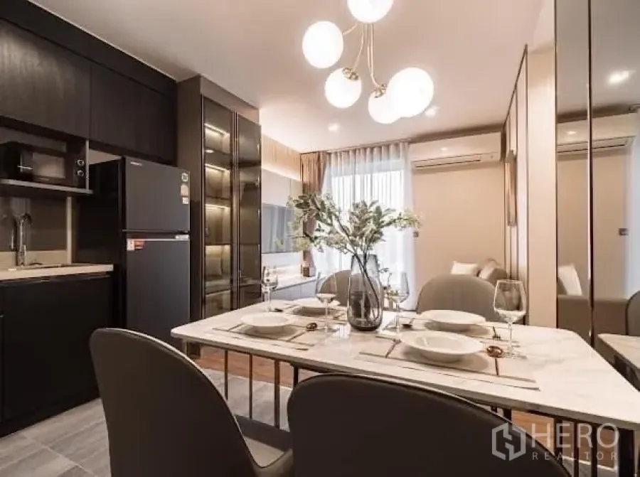Condominium for rent in Watthana, Bangkok - Dining table set for four beside kitchen and mirrored wall.