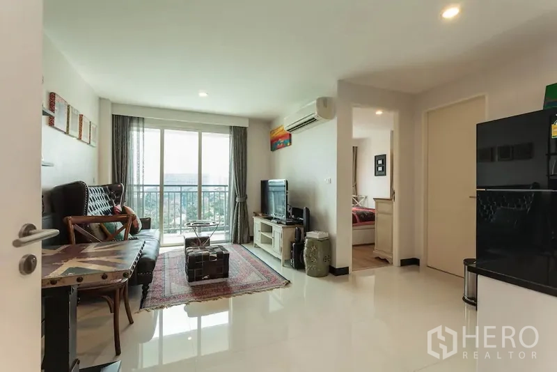公寓 出租在Khlong Toei, Bangkok - 明亮客厅，带阳台和城市景观，电视柜与通往卧室的门。
