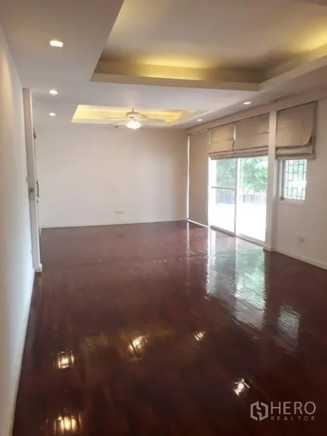 บ้าน ให้เช่าในWatthana, Bangkok - ห้องนั่งเล่นโปร่ง ฝ้าเพดานซ่อนไฟ พื้นไม้ และประตูกระจกบานเลื่อนออกสู่สวน