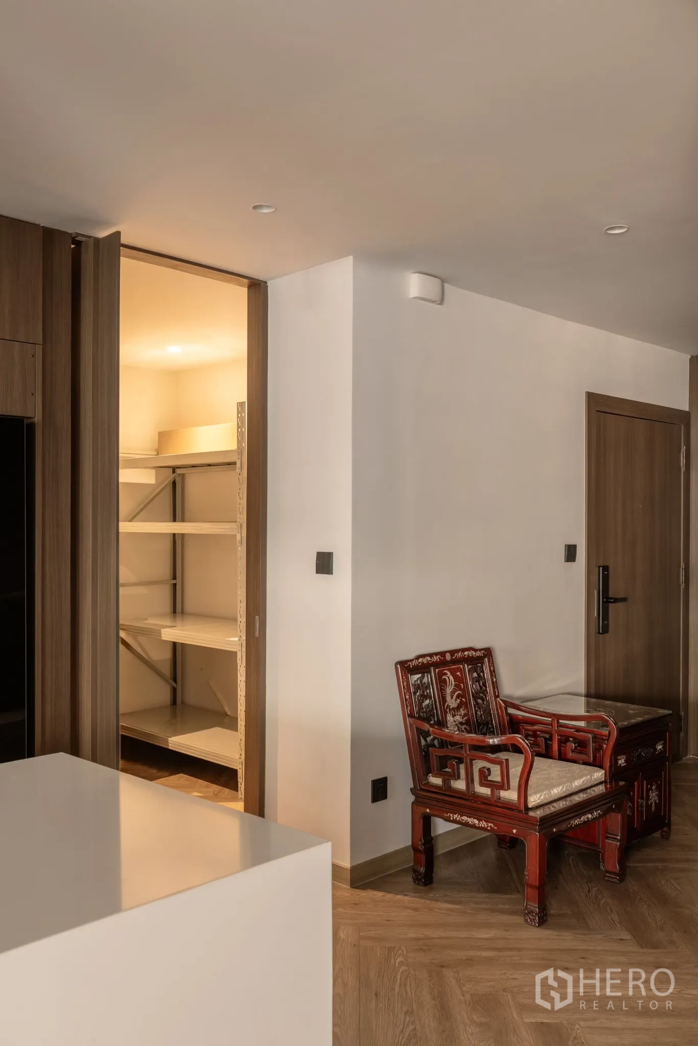 Condominium for sale in Khlong Toei, Bangkok - Pantry or storage room with illuminated shelving next to a vintage red wooden chair.
