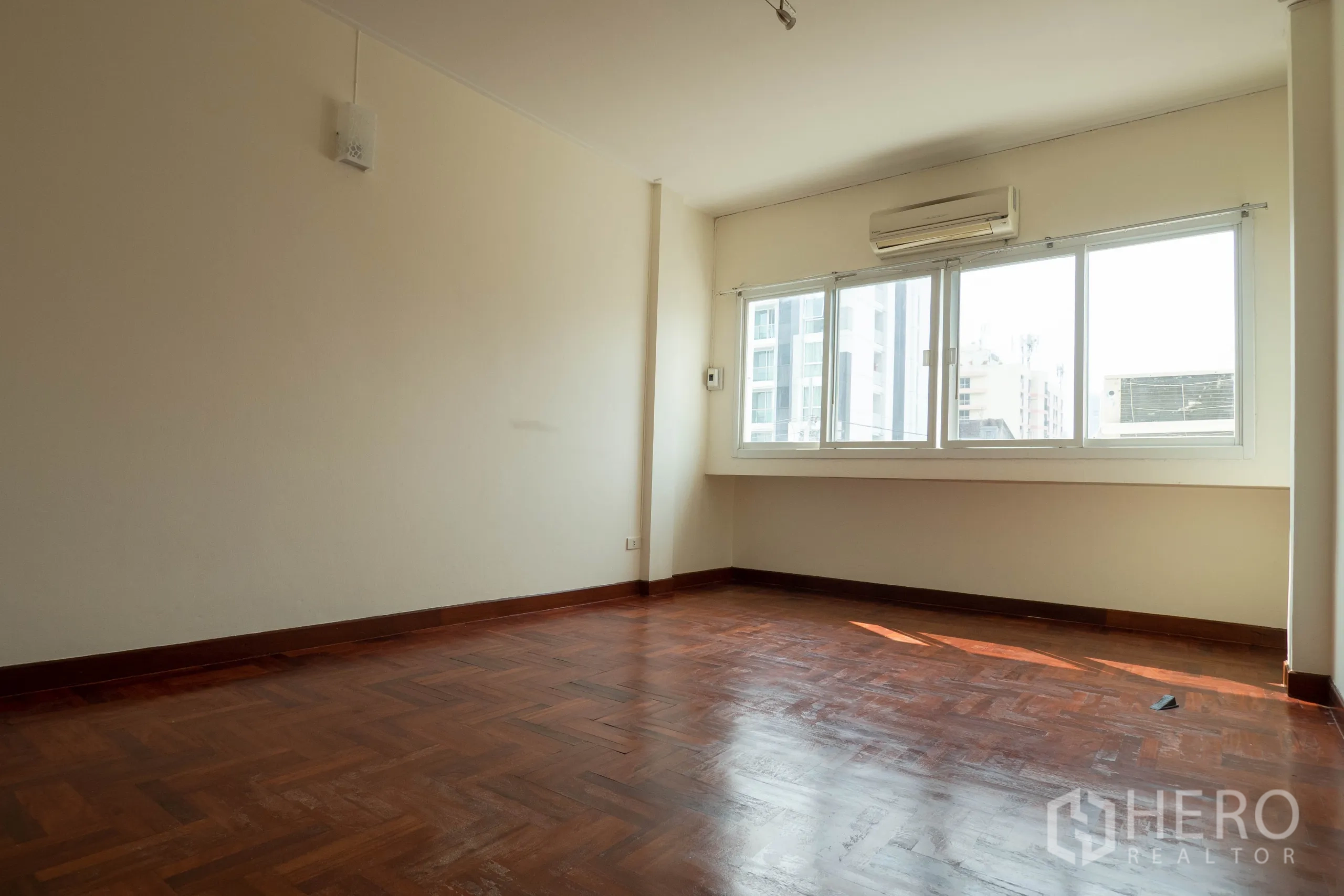 Townhouse for rent in Khlong Toei, Bangkok - Large room with wide windows, air conditioning and city view over wood floors.