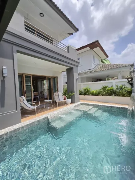 独立式住宅 出售在Suan Luang, Bangkok - 清澈泳池与水景，映衬现代两层立面与阳台。