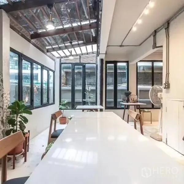 สำนักงานที่บ้าน ให้เช่าในBang Rak, Bangkok - มุมประชุมสว่างด้วยสกายไลท์ หน้าต่างกรอบดำ และต้นไม้ในอาคาร