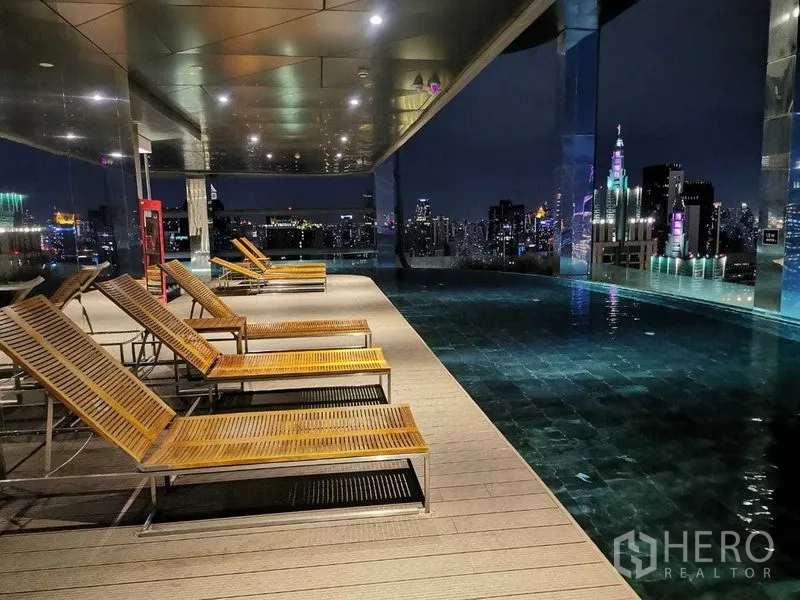 คอนโด ให้เช่าในRatchathewi, Bangkok - สระว่ายน้ำอินฟินิตี้บนดาดฟ้ายามค่ำ พร้อมเตียงอาบแดดและวิวกรุงเทพฯ