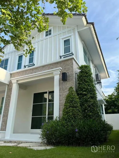 Detached House for rent in Bang Phli, Samut Prakan - Corner view of the house with landscaped shrubs and lawn.
