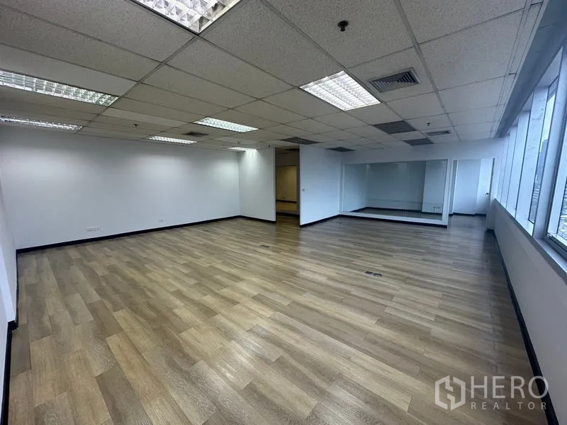 办公空间 出租在Phra Khanong, Bangkok - 大型开放办公室，木地板与一排侧窗引入自然光。