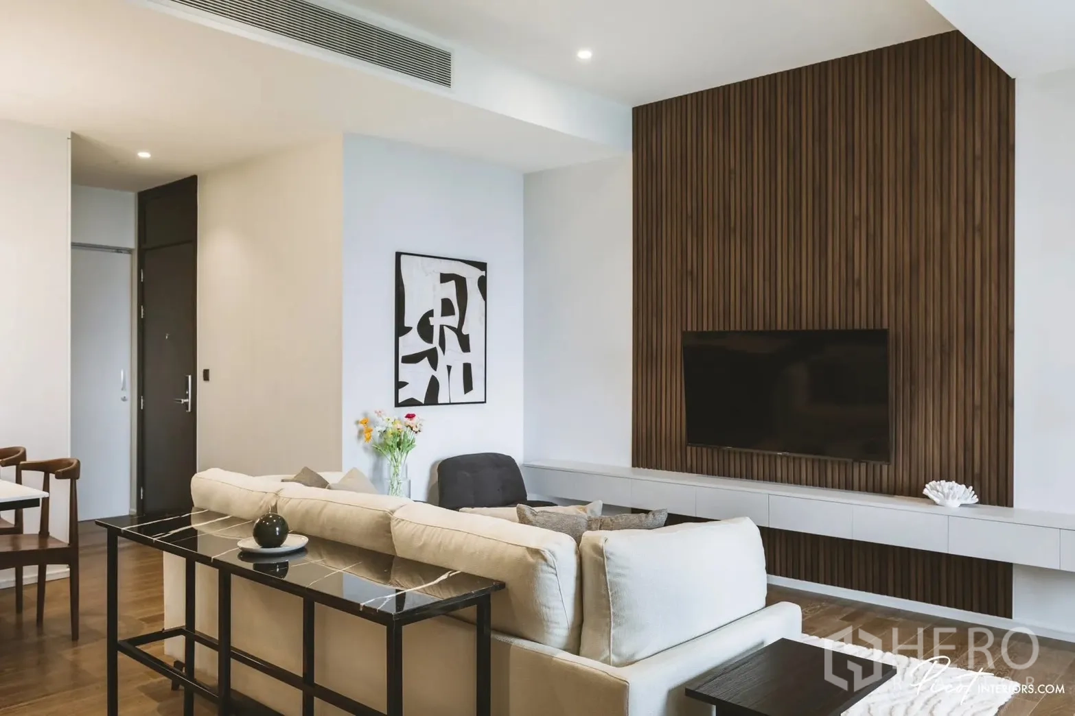 Condominium for rent in Pathum Wan, Bangkok - Contemporary living room with cream sofa facing a wood-slat TV feature wall and console.