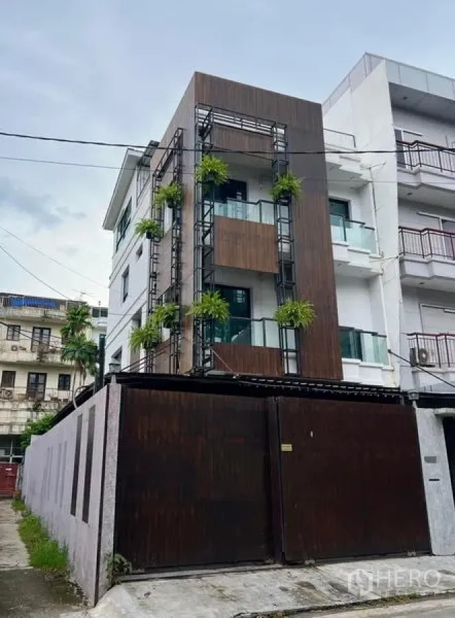 Townhouse for rent in Phaya Thai, Bangkok - Front elevation of a modern townhouse with wood panels, balconies and greenery.