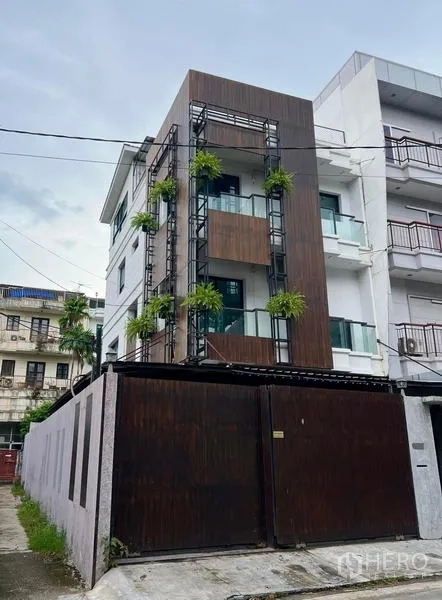 Townhouse for rent in Phaya Thai, Bangkok - Front elevation of a modern townhouse with wood panels, balconies and greenery.
