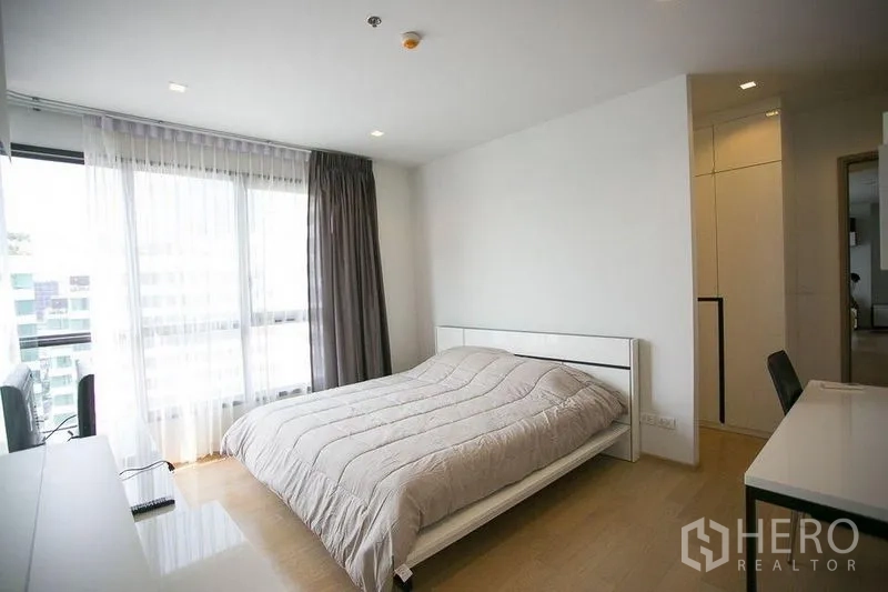 公寓 出租在Watthana, Bangkok - 宽敞卧室，浅木地板、双人床与采光充足的窗户。