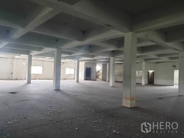 Shophouse for rent in Bang Bo, Samut Prakan - Spacious open-plan interior with concrete floor, grid ceiling and square columns in an empty shophouse level.