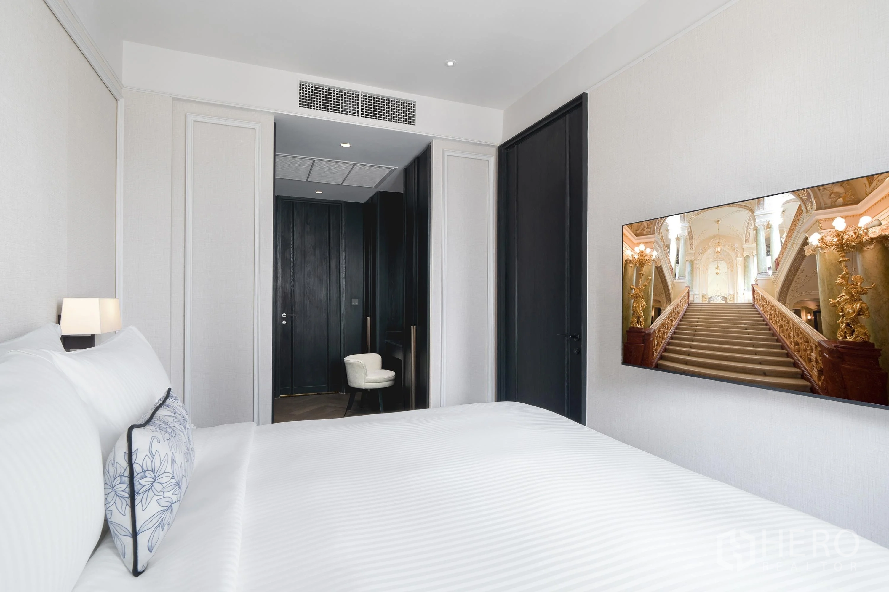 Condominium for rent in Khlong Toei, Bangkok - Bedroom view toward dark wood doors and a built-in dressing vanity.