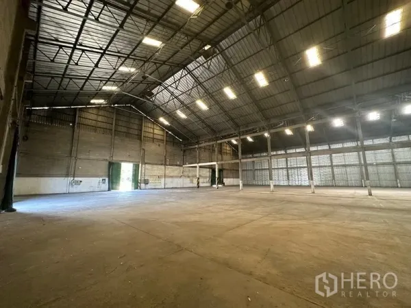 货栈 出租在Mueang Pathum Thani, Pathum Thani - 仓库内角度，顶灯明亮，通风百叶与宽大的出入口。