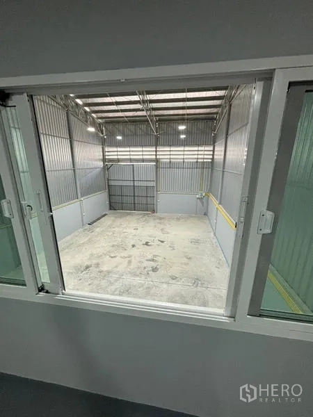 货栈 出租在Mueang Pathum Thani, Pathum Thani - 从办公室窗户俯瞰仓库地面与入口门。