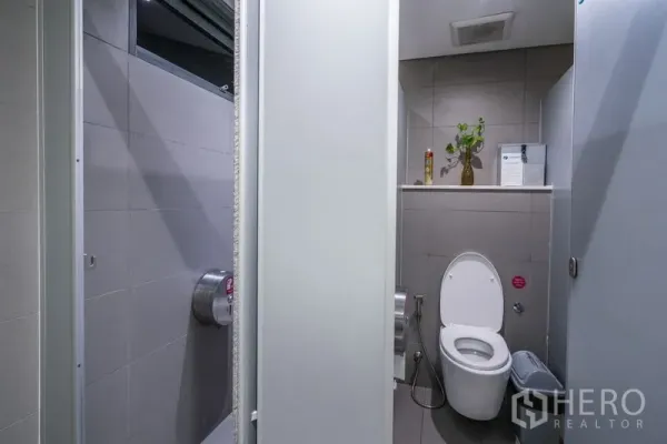 Office Space for rent - Clean tiled office restroom with toilet, bidet spray, and shelf decor.