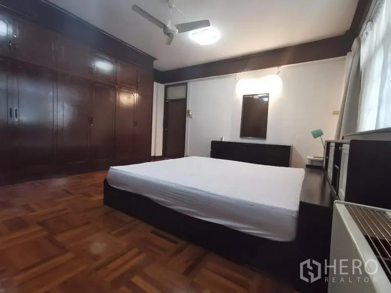 房间 出租在Khlong Toei, Bangkok - 主卧带大面积嵌入式衣柜、吊扇与木地板。
