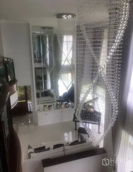 Detached House for sale in Saphan Sung, Bangkok - Double-height living room with floor-to-ceiling windows, mirrored wall and crystal chandelier.