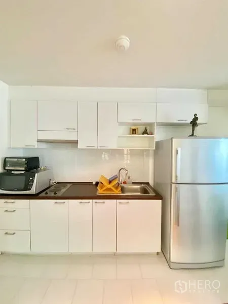คอนโด ให้เช่าในWatthana, Bangkok - ครัวขนาดกะทัดรัดโทนสีขาวพร้อมตู้เก็บของ เตา ซิงก์ และตู้เย็นสแตนเลส
